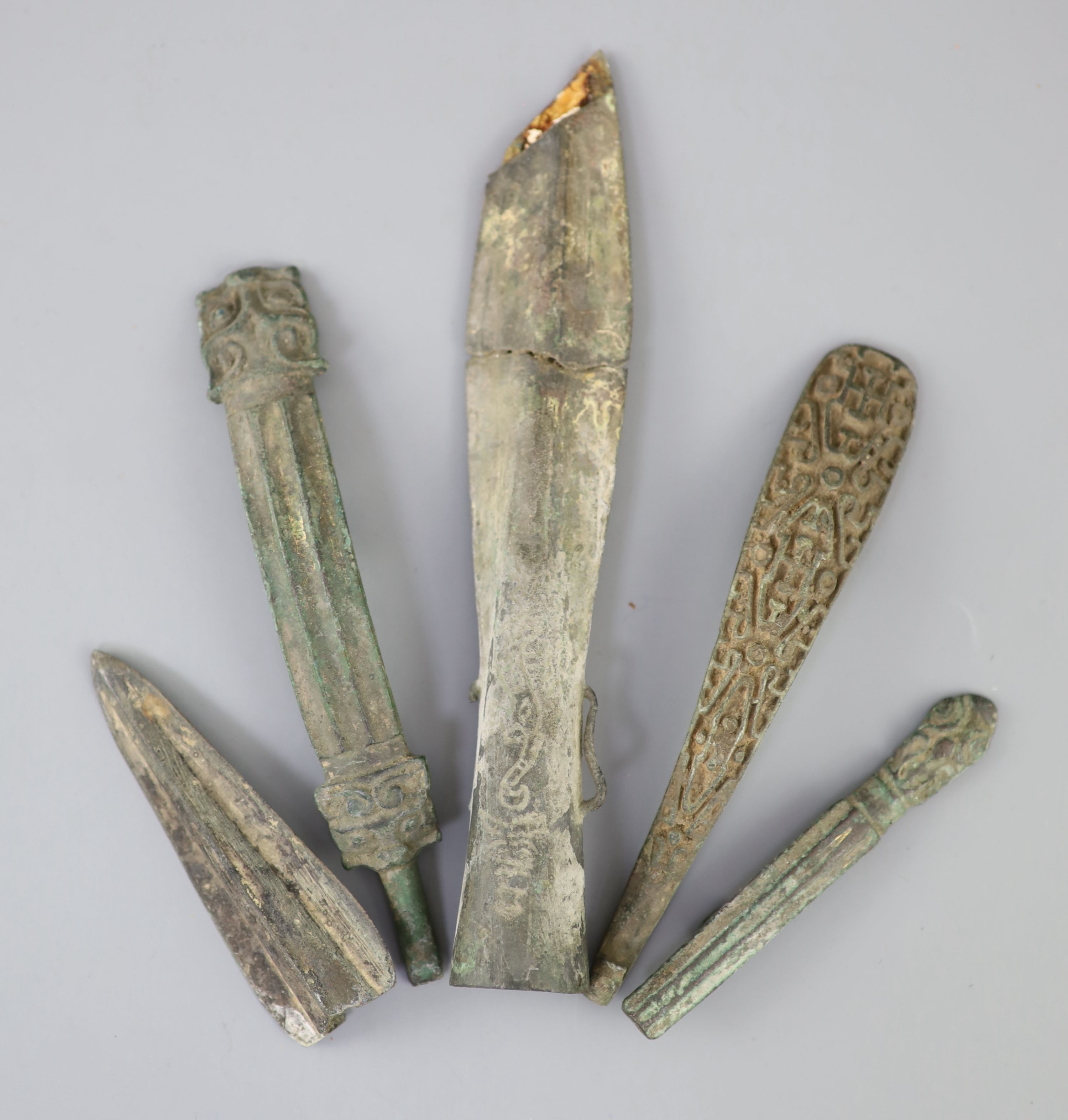 Three Chinese archaic bronze belt hooks and two spear heads, Warring States / Han dynasty